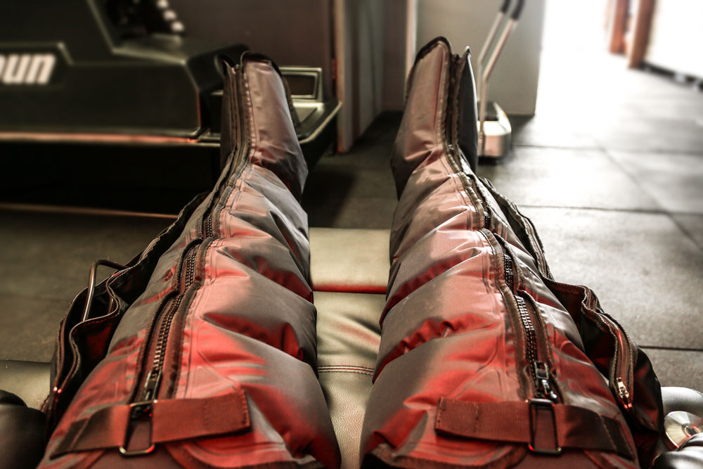 Leg compression boots connected to a pneumatic system for circulation and recovery support.
