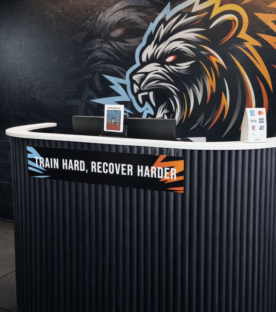 Reception desk inside a recovery centre, featuring a curved counter, branded signage, and bold lion artwork on the wall behind.